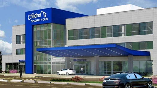 A white car is parked in front of a hospital building.