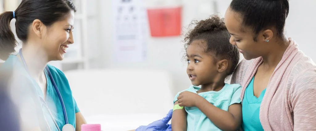 A young girl wearing a blue shirt and holding her arm up.