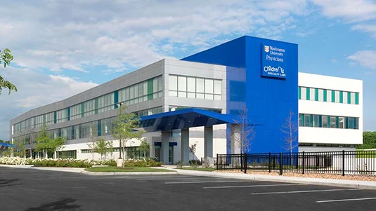 A blue hospital building with a white roof and a blue sign.